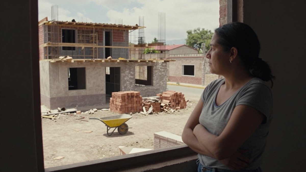 Persona mirando desde una ventana hacia otra vivienda al preparar la transición de renta a compra